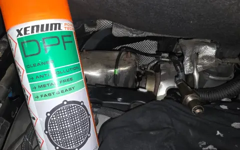 Bouteille de nettoyant FAP Xenum à côté d'un capteur et de pièces de moteur.