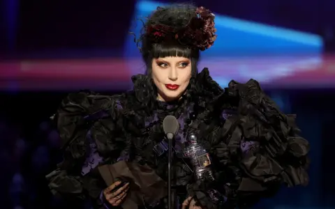 Lady Gaga w Polsce, w czarnej, falbaniastej sukni z fioletowymi wstawkami, odbiera nagrodę.