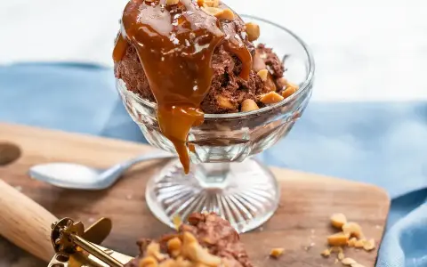 En skål med chokladglass, toppad med kolasås och nötter. Perfekt för ett chokladglass recept!