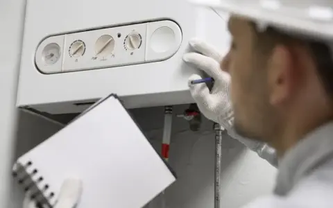 Técnico revisa una caldera de condensación, anotando detalles en su libreta.