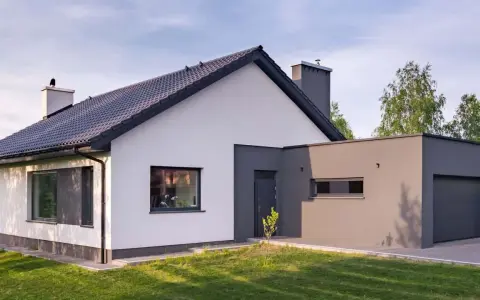 Nowoczesny dom z białymi i grafitowymi akcentami, prezentujący najmodniejsze kolory elewacji.