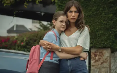 Erin Carter abbraccia una bambina con uno zaino rosa. La donna sembra preoccupata, la bambina protetta.