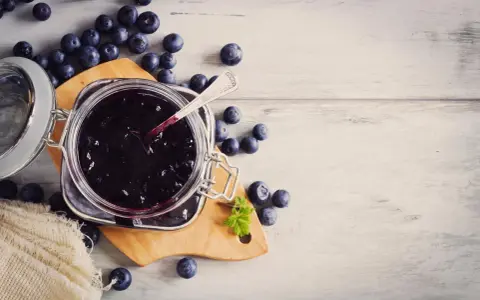 Frische Heidelbeeren und selbstgemachte Heidelbeermarmelade im Glas, bereit zum Genießen.