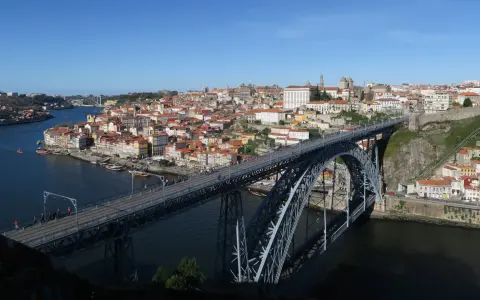 El icónico puente de Oporto cruza el río Duero, conectando la ciudad con sus coloridas casas y barcos turísticos.