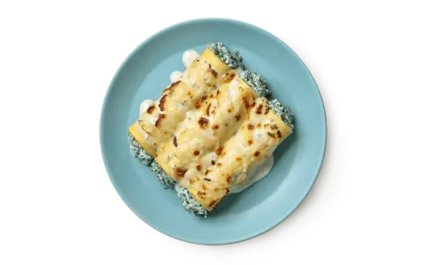 Tre cannelloni ripieni di ricotta e spinaci, gratinati al forno con besciamella e formaggio fuso, serviti su un piatto azzurro.