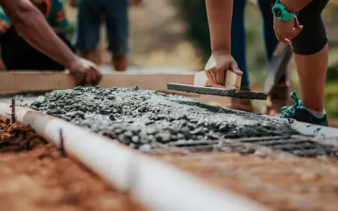 Pracownicy wyrównują świeży beton na fundamencie. Jaki beton na fundament b20 czy b25?