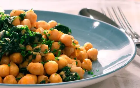 Garbanzos salteados con espinacas y ajo, una de las muchas recetas con garbanzos de bote, servidos en plato azul.