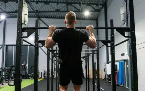 Man tränar pull ups i ett modernt gym.