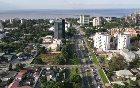 Widok z lotu ptaka na nowoczesne miasta w Afryce, z wysokimi budynkami, zielenią i ruchliwą drogą w tle.