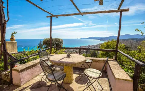 Terrazza con tavolo e sedie, vista mare e colline. Ideale per agriturismi entroterra ligure.