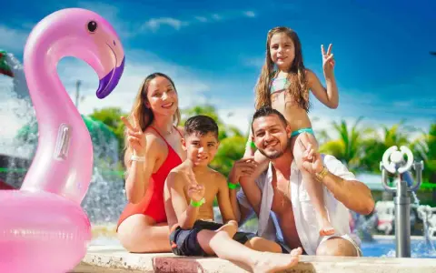 Szczęśliwa rodzina z dziećmi, gdzie z dziećmi na wakacje, pozuje przy basenie z dmuchanym flamingiem.