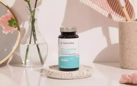 Flacon de cure de collagène marin Novoma, posé sur un plateau décoratif, près d'un miroir, d'une fleur et d'une brosse à dents.