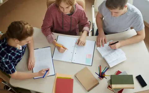 Trzech studentów pracuje nad pracą licencjacką, analizując metody badawcze.