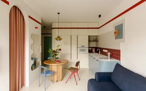 Un angolo di casa moderna con richiami alle case tipiche italiane: un tavolo rotondo, sedie colorate e una cucina funzionale.