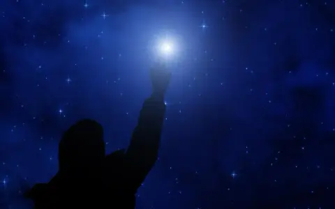 Sylwetka człowieka sięga ku jasnej gwieździe polarnej na tle nocnego, gwiaździstego nieba.