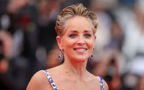 Sharon Stone luce un elegante corte bixie, con pendientes de zafiro y un vestido blanco con detalles azules.