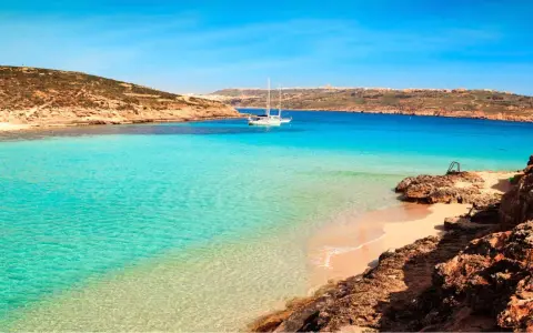 Traumhafter Malta Strand mit türkisfarbenem Wasser, einer einsamen Bucht und einem Segelboot. Perfekt für einen entspannten Urlaub.