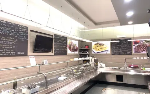 Interior of a restaurant with a display counter, menu boards, and food images.
