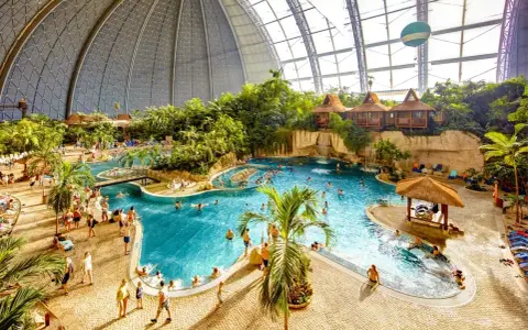 Wielki tropikalny basen pod kopułą, z palmami, wodospadami i domkami. Sprawdź nasz tropical island cennik, by zaplanować wakacje!