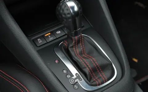 Zbliżenie na dźwignię automatycznej skrzyni biegów z oznaczeniami P, R, N, D, S. Widoczne przyciski trybów Comfort i Sport.