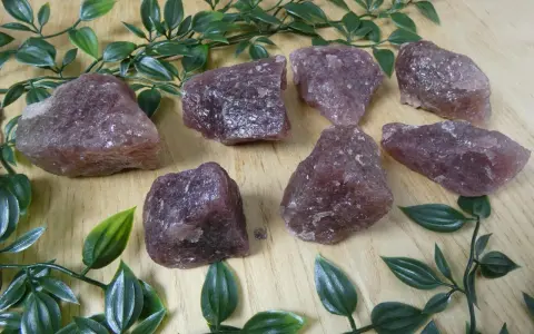 Gruppo di quarzo fragola grezzo su fondo di legno. Le sue proprietà sono note per favorire l'amore e la guarigione emotiva.