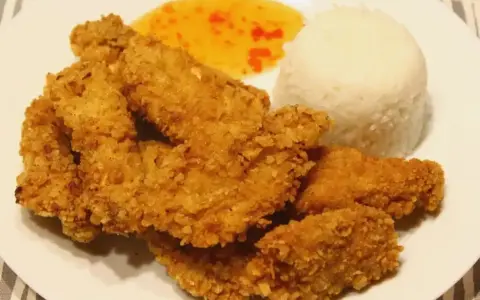 Chrupiący kurczak w panko, ryż i słodko-kwaśny sos na białym talerzu.