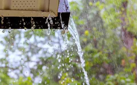 Acqua piovana che scorre da una grondaia, un esempio di impianto recupero acqua piovana pro e contro.