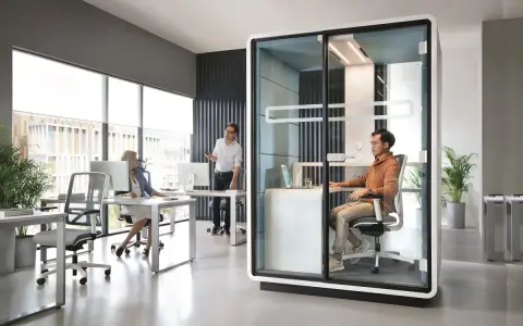 Aménagement open space ergonomique : un bureau moderne avec des postes de travail ouverts et une cabine insonorisée pour la concentration.