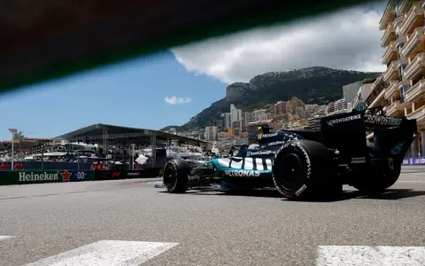 Coche de clasificación F1 en Mónaco, con el mar y edificios de lujo de fondo.