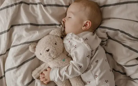 Kleines Kind schläft friedlich mit Teddybär. Die **Schlafregression 1 Jahr** ist eine Herausforderung, aber dieser süße Anblick tröstet.