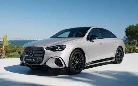 La Mercedes Classe C 2026, un'elegante berlina elettrica, si presenta con un design moderno e sportivo, con cerchi neri e uno sfondo marino.