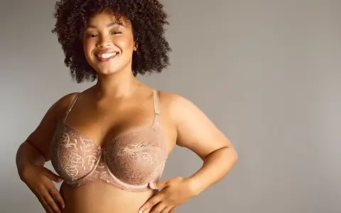 Donna sorridente con tette grandi perfette in reggiseno di pizzo color carne.