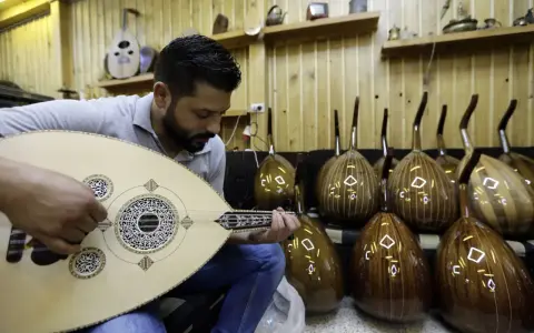 Un joueur de oud expérimenté accorde son instrument, entouré d'autres ouds prêts à être joués.