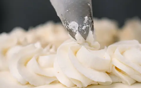 Dekorowanie tortu puszystym kremem bananowym za pomocą rękawa cukierniczego.