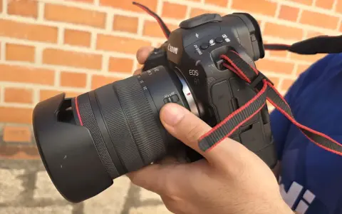 Mano sosteniendo una cámara Canon R1 con lente, lista para capturar momentos.