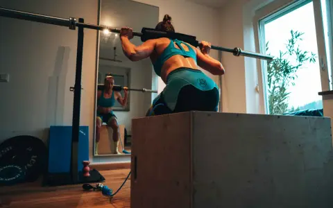 Frau beim Krafttraining für Triathlon, macht Kniebeugen mit Langhantel.