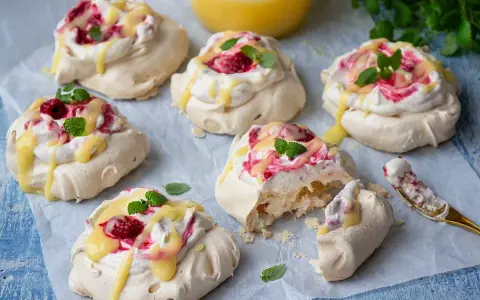Små pavlovakakor med grädde, hallon och citronsås. En perfekt liten dessert!