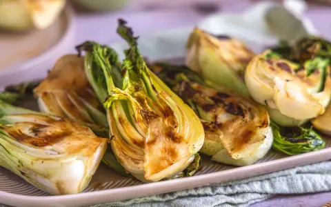 Halbierte Pak Choi-Stücke, die auf einem Teller mit Grillspuren liegen. Köstlich und gesund!