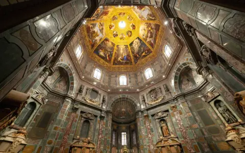 Intérieur de la Chapelle des Médicis, dôme orné de fresques dorées et de peintures religieuses, murs décorés de marbre et de sculptures.
