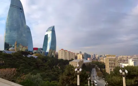 Płomienne wieże Flame Towers w Baku, które warto zobaczyć, górują nad miastem. W tle widać panoramę miasta i zielone drzewa.