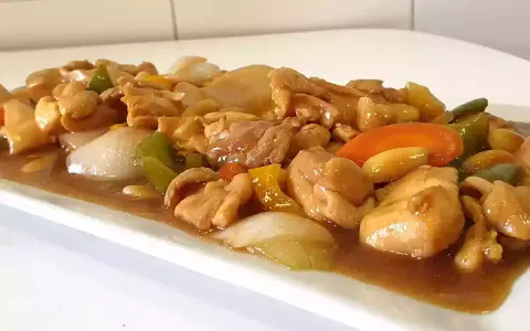 Delicioso pollo con almendras, pimientos y cebolla en una salsa dorada.