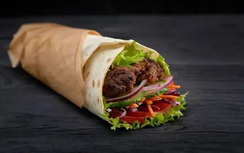 Kebab zawinięty w placek z mięsem, sałatą, pomidorem, ogórkiem i cebulą.