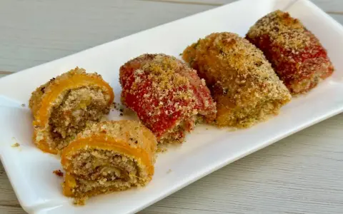 Involtini di peperoni ripieni e gratinati, serviti su un piatto bianco.