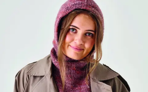 Ung kvinna med stickad balaclava i rosa toner och en beige kappa. Perfekt för barn som vill sticka en egen balaclava.