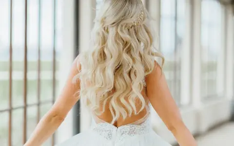 Długie, falowane blond włosy ozdobione złotą spinką. Fryzura w stylu lat 20. idealna na ślub.