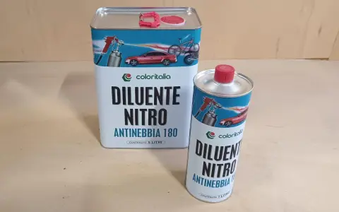 Due barattoli di diluente nitro Coloritalia, uno da 5 litri e uno da 1 litro, con grafica di auto e bici. La differenza tra diluente sintetico e nitro è nella composizione.