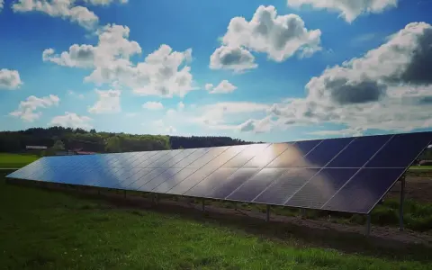 Lång rad solpaneler fångar solljuset under en molnig himmel. Solkraft EMK AB bidrar till en grönare framtid.