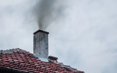 Dym wydobywający się z komina na tle pochmurnego nieba.
