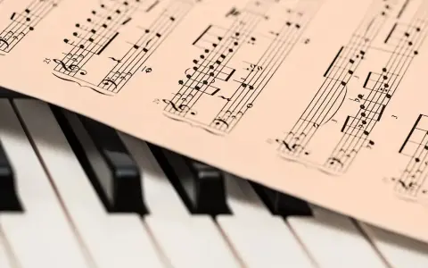 Partytura muzyczna na klawiaturze pianina. Widoczne nuty i klucze, które oddają bogate **cechy muzyki barokowej**.