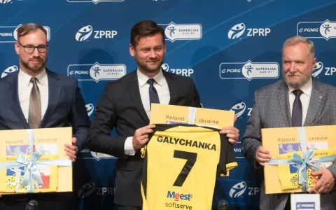 Trzech mężczyzn w garniturach prezentuje koszulkę z napisem "Galychanka" i numerem 7. Obok nich żółte pudełka z napisami "Poland Ukraine".